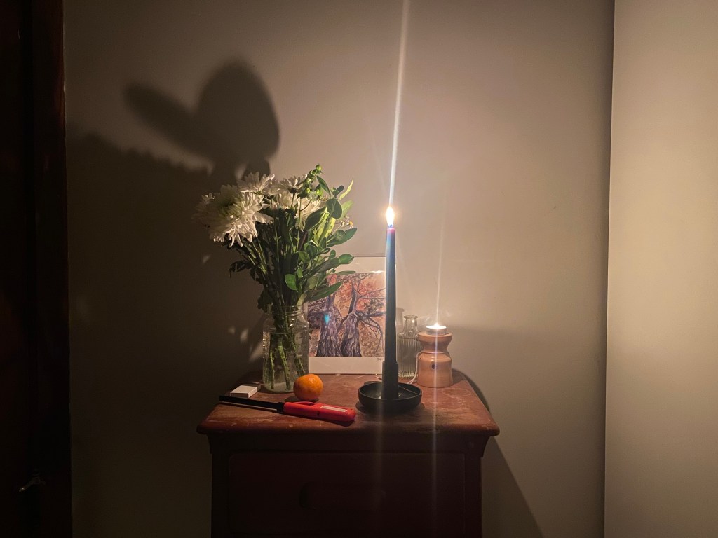 Black candle for protection. Flowers for peace. Portrait of twin trees.